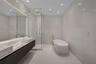 Floating dual vanity featuring rectangular vessel sinks, floor-to-ceiling stone-tiled walls, glass-enclosed shower, and a freestanding soaking tub