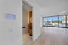Floor-to-ceiling glass wall, wood-finish flooring, recessed lighting, and wall-mounted smart home control panel, featuring a powder room with cylindri