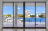 Floor-to-ceiling multi-panel sliding glass doors with dark metal framing, expansive tiled terrace, and structural cylindrical column