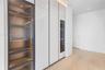 Custom millwork featuring floor-to-ceiling high-gloss cabinetry, integrated wine refrigeration, glass-front display shelving with LED illumination, an