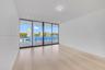Floor-to-ceiling sliding glass panels with metal framing, wood-finish flooring, and expansive water exposure