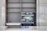 Floor-to-ceiling cabinetry with open shelving, integrated stainless steel double wall ovens, smooth-surface cooktop, and stone countertop