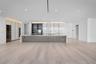 Minimalist kitchen featuring an expansive center island with a stone countertop, floor-to-ceiling cabinetry with integrated display shelving, built-in