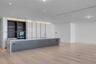 Modern kitchen featuring a expansive island with stone waterfall countertops, high-gloss white cabinetry, integrated open shelving, matte-finish lower