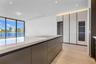 Kitchen featuring a large central island with a stone countertop and integrated cooktop, full-height gloss cabinetry with built-in refrigeration, wood