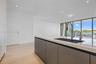 Kitchen island featuring flat-panel cabinetry, light-toned stone-finish countertop, integrated sink, and polished metal faucet, complemented by wood-f