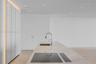 Minimalist kitchen island featuring a stone countertop, flush-mount cooktop, integrated downdraft ventilation, and a high-arc faucet, complemented by 