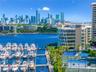 Waterfront property featuring a private marina, professional-grade tennis courts, and multi-level architectural glass facade with a metropolitan skyli