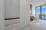 Stone-tiled flooring, wall-mounted wood-finish vanity, freestanding soaking tub, recessed ceiling lighting, and floor-to-ceiling glass sliding doors