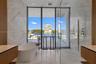 Floor-to-ceiling glass windows, stone-finish wall cladding, freestanding soaking tub, glass-enclosed shower, and dual wood-finish floating vanities