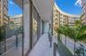 Covered balcony featuring expansive glass sliding doors, stone-tiled flooring, and a frameless glass balustrade