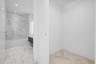 Bathroom featuring stone-finish wall and floor tiling, a soaking tub with integrated shower hardware, a floating vanity with a vessel sink, and herrin