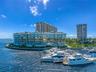 Waterfront residential complex featuring floor-to-ceiling glass paneling, wraparound structural balconies, and a dedicated deep-water boat slip marina