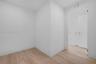 Neutral interior space featuring wood-finish flooring, smooth white wall finishes, and minimalist interior doors with metallic lever handles