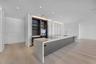 Modern kitchen featuring a waterfall-edge stone island, integrated cabinetry, wood-finish flooring, recessed lighting, and built-in appliances