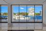 Floor-to-ceiling glass sliding doors, expansive waterfront exposure, polished stone countertop, and light-toned tile flooring