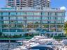 Modern mid-rise building featuring floor-to-ceiling glass facades, wrap-around balconies with glass railings, and direct access to a private marina