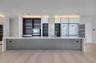 Large kitchen island featuring a stone waterfall countertop, integrated refrigeration, floor-to-ceiling cabinetry with open shelving, recessed lightin