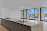 Kitchen island featuring a waterfall stone countertop, integrated cooktop, recessed lighting, floor-to-ceiling glass wall, and wood-finish flooring