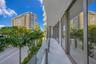 Curved balcony featuring light-toned stone flooring, floor-to-ceiling glass panel railings, and expansive glass wall paneling