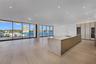 Open-concept interior featuring floor-to-ceiling glass walls, expansive kitchen island with a stone-finish waterfall countertop, built-in floor-to-cei