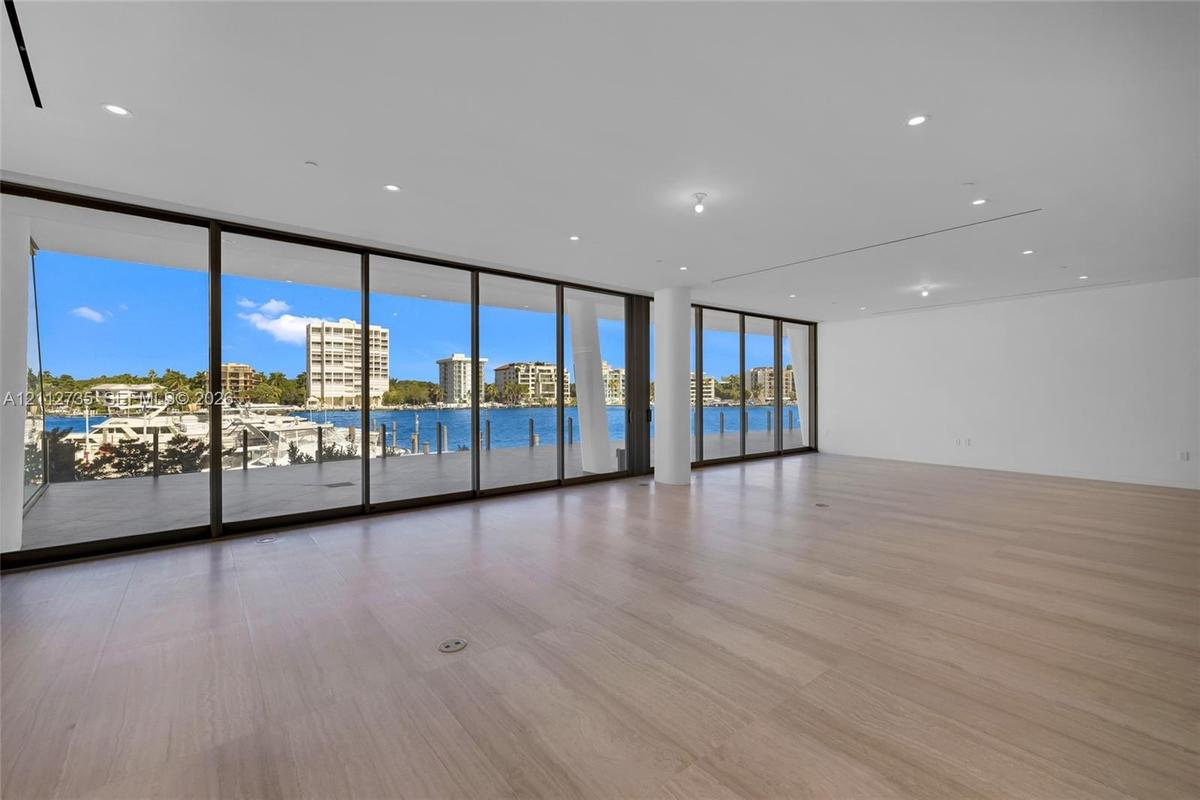 Expansive interior featuring floor-to-ceiling glass sliding doors, wood-finish flooring, recessed lighting, and a covered exterior deck