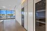 Floor-to-ceiling glass wall, custom cabinetry with high-gloss finish, integrated wine refrigeration, and wood-finish flooring