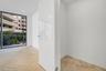 Herringbone-patterned wood-finish flooring, floor-to-ceiling glass window, and high-gloss white interior door