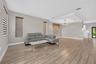 Open concept interior featuring wood-finish tile flooring, recessed tray ceiling, multi-light chandelier, and horizontal window shades