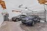 Two-car garage featuring a concrete floor, sectional overhead door, built-in wooden wall shelving, and a dedicated water heater
