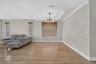 Tray ceiling, multi-light modern chandelier, wood-finish flooring, and horizontal window shades