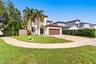 Two-story exterior featuring a tile roof, stucco finish, arched entryway, and a paver driveway leading to an attached garage