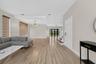 Open floor plan featuring wood-finish flooring, tray ceiling, statement chandelier, and double-paned sliding glass doors