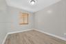 Room featuring neutral-toned walls, wood-finish flooring, a single window with wood-finish blinds, and a circular flush-mount ceiling light fixture
