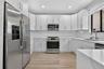 Kitchen featuring white Shaker-style cabinetry, stainless steel appliances, quartz countertops with a subtle veining pattern, white subway tile backsp