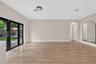 Open-concept room featuring wood-finish flooring, floor-to-ceiling glass panel double doors with black frames, a high-arched passageway, and a large a