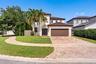 Two-story stucco exterior featuring a tiled roof, arched entryway, brick-paver driveway, and an attached two-car garage