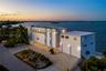 Waterfront residence featuring a rooftop terrace, multi-level exterior structure, two-car garage, concrete driveway, and pilings foundation