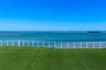 Outdoor space featuring synthetic turf and a white horizontal-slat metal railing, set against a waterfront backdrop