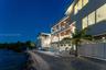 Multi-level exterior featuring stacked balconies with glass railings, a swimming pool with tile surround, and direct waterfront access via a rock-line