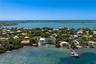 Waterfront estate featuring a multi-level structure with a flat roof, private dock, direct water access, and exterior balconies