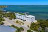 Waterfront property featuring a private dock, expansive rooftop terrace, two-car garage, and established tropical landscaping