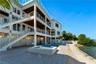 Multi-level residence featuring tiered outdoor balconies with horizontal railings, stone-tiled patio, in-ground swimming pool, and integrated spa