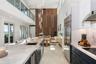 Double-height ceilings, floor-to-ceiling wood-panel accent wall, dual-tone cabinetry with stone-finish countertops, stainless steel integrated applian