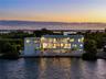 Waterfront residence featuring multi-level balconies, expansive glass windows, a flat roofline, and a private dock