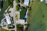 Waterfront estate featuring a direct shoreline, private swimming pool, concrete paved driveway, and artificial turf roof installation