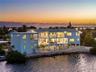 Waterfront multi-story residence featuring tiered balconies, a rooftop deck, exterior staircase, and a ground-level swimming pool