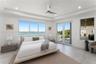 Tray ceiling with recessed lighting, floor-to-ceiling windows, modern ceiling fan, and glass-paneled double doors opening to a balcony
