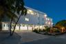 Multi-story exterior featuring a stilted foundation, concrete driveway, recessed ground-level parking, and native landscaping