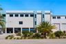 Multi-level exterior featuring smooth stucco finish, tiered flat roofline, oversized rectangular windows, ground-level covered parking, and attached m